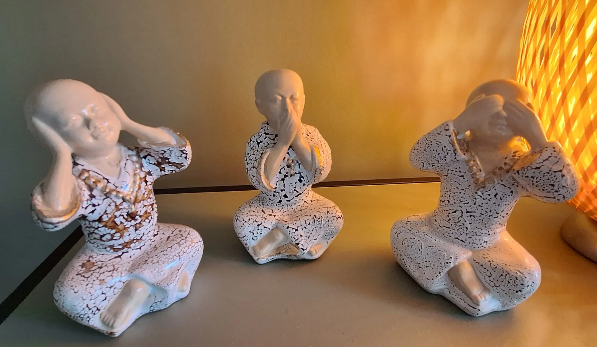 Trois statuettes de moines, posées côte à côte : l'une se bouche les oreilles, l'autre la bouche, la troisième les yeux.